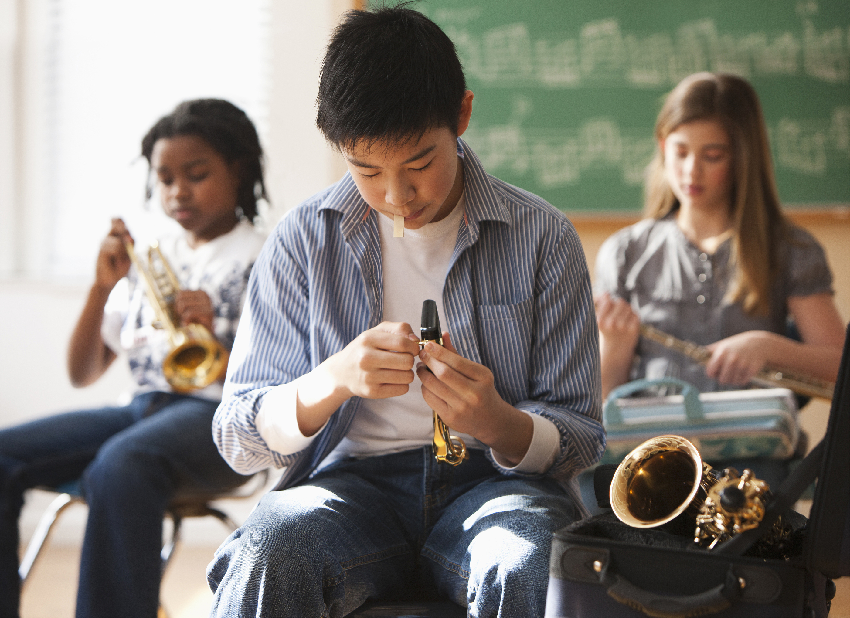 Young man putting a reed on his saxophone